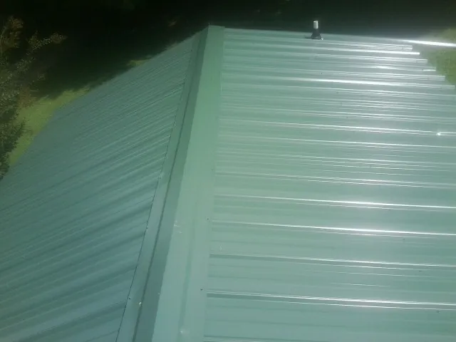 New green metal panels meeting at the ridge of a roof — Flat Roof Repair work by our crew in Verbena