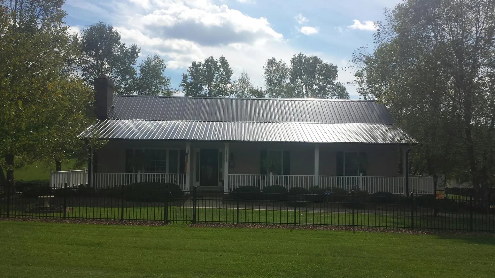 Gray metal roof on a brick ranch with a full width front porch — Gutter Guard Installation work by our crew in Verbena