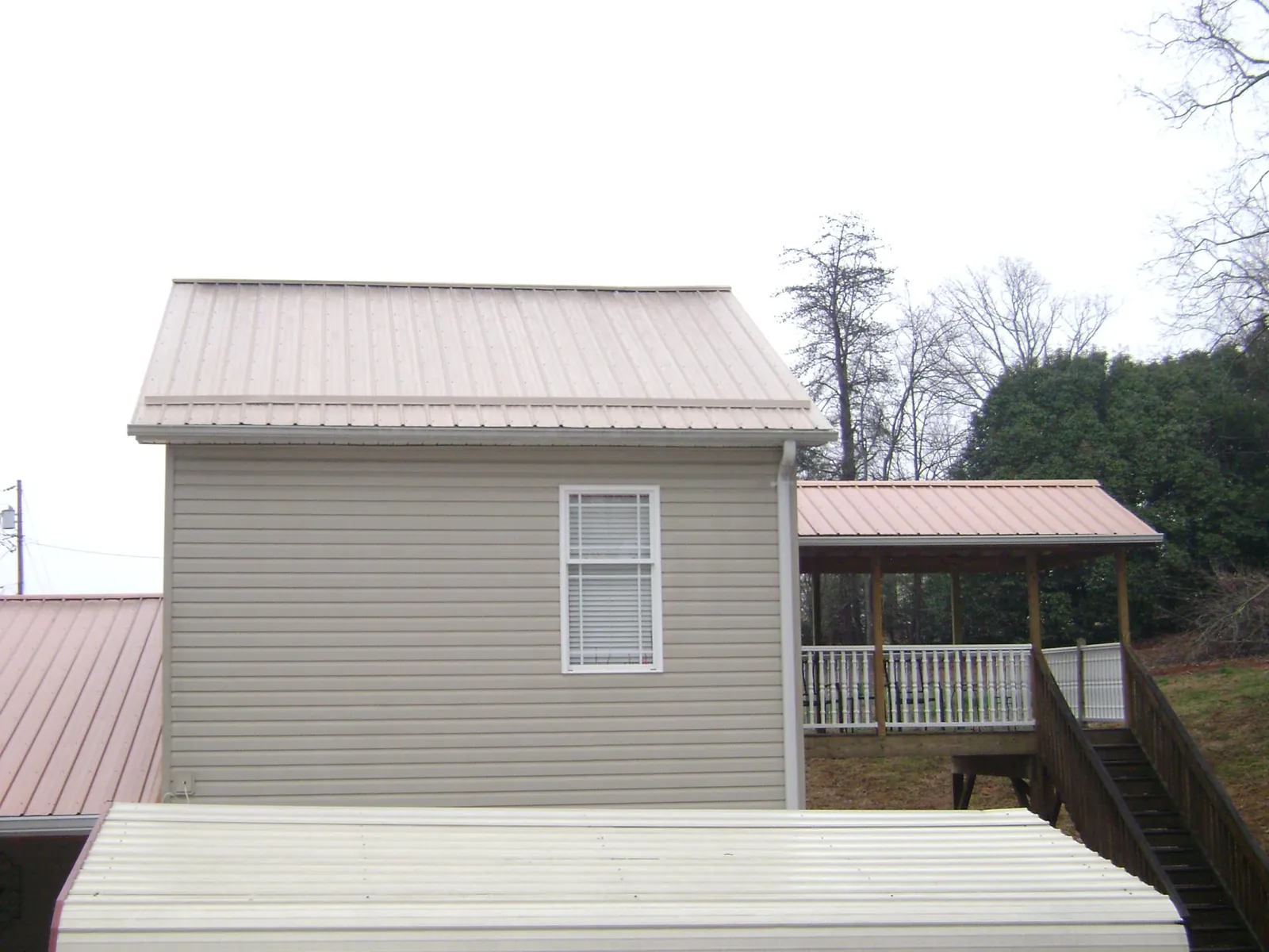 Tan metal roofs on a two story addition and attached porch, from a Roof Replacement job in Verbena