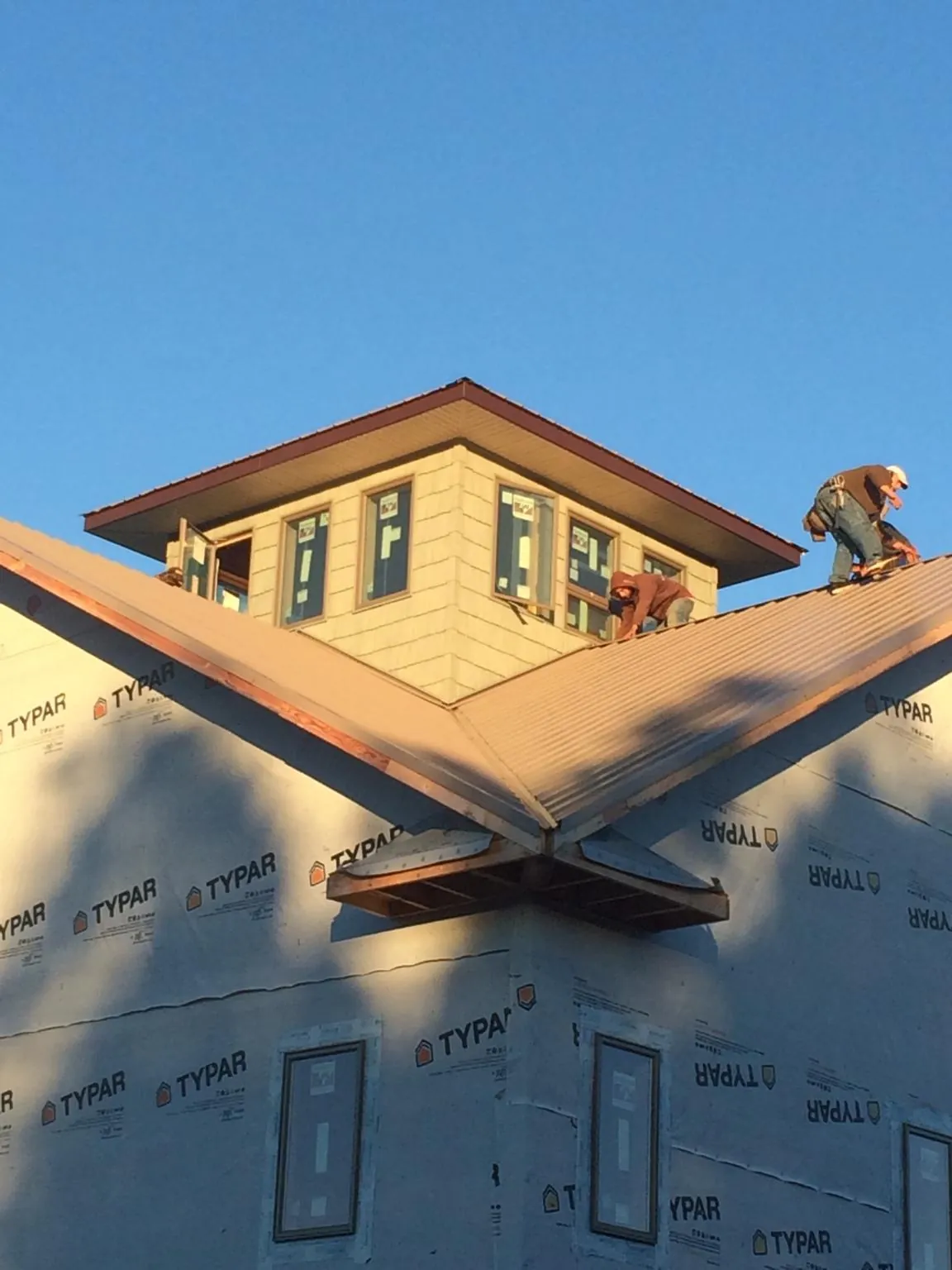 Roofers working around a rooftop cupola on a new metal roof at sunset — Roof Waterproofing in Verbena by Roofing Brothers